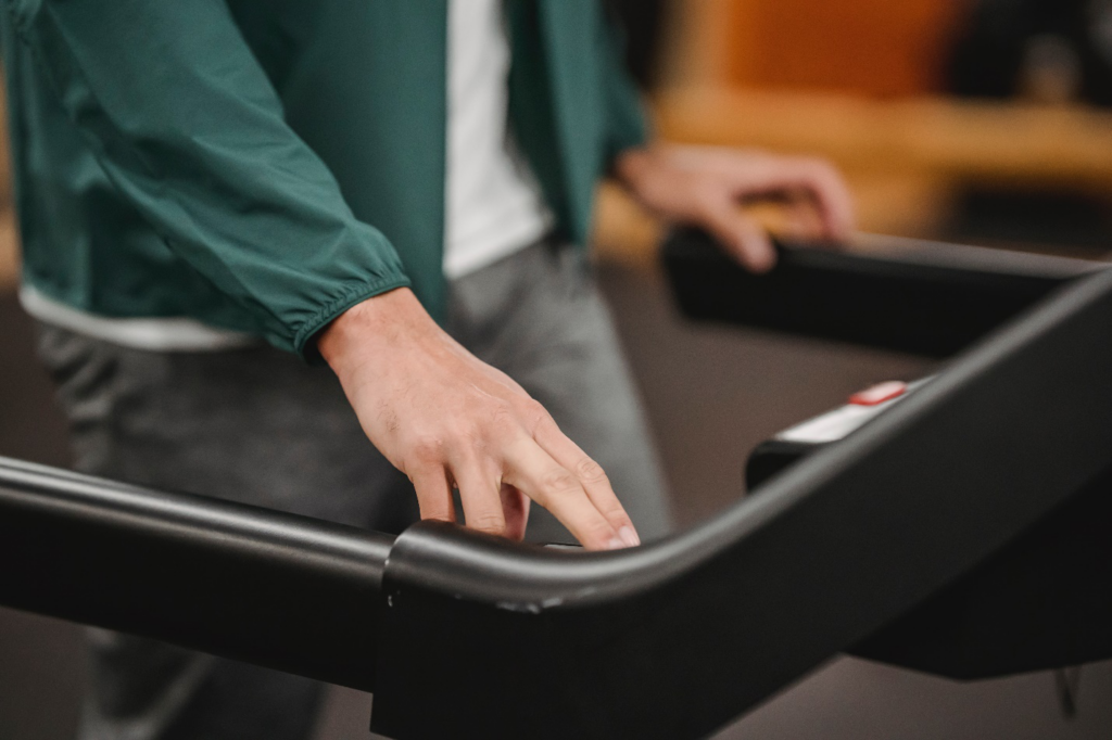 A hand is pushing a button on a treadmill
