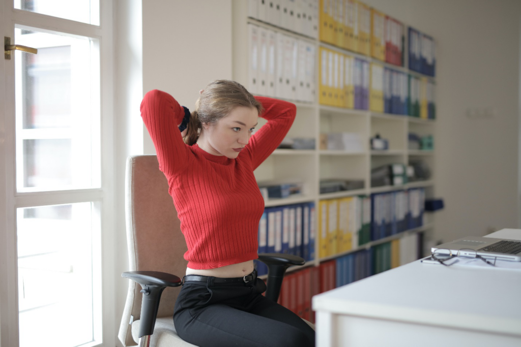 A woman at her desk gets ready to exercise while at work