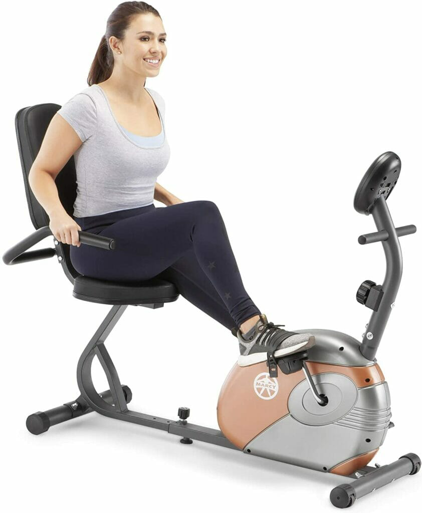 A woman in a grey top and black lowers sitting on an exercise bike