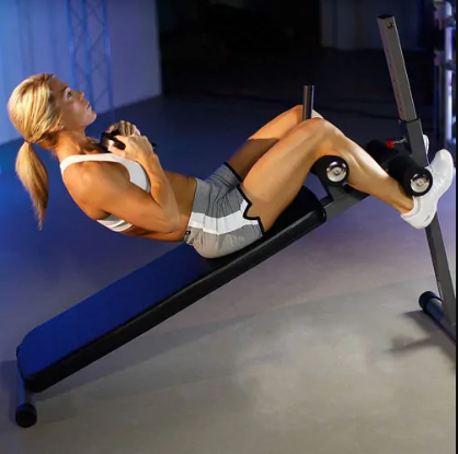 A woman is mid sit-up holding a weight to her chest on an exercise bench