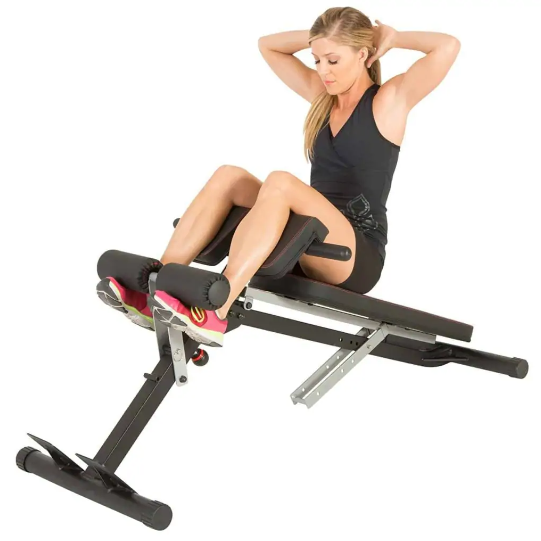A woman sits up on an exercise bench with her hands behind her head